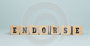 The word ENDORSE made from wooden cubes on blue background photo