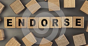 The word ENDORSE on small wooden blocks at the desk. Top view photo