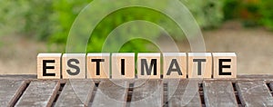 Word ESTIMATE is made of wooden building blocks lying on the table and on a light green background. Concept