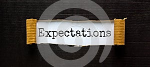 The word `expectations` appearing behind torn black paper. Beautiful background. Business concept