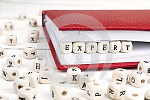 Word Expert written in wooden blocks in notebook on white wooden