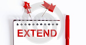 The word EXTEND is written in the notebook with office tools