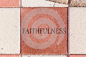 The Word Faithfulness on a sidewalk paver