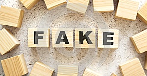 The word FAKE consists of wooden cubes with letters, top view on a light background.