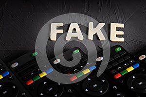 The word fake is made of wooden letters on a dark background