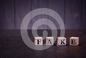 The word fake on wooden cubes, on a dark background, light wooden cubes signs, symbols signs
