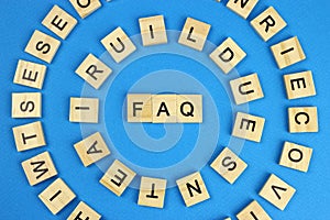 The word faq is made of wooden letters on a blue background