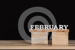 Word February from wooden letters. Wooden calendar. Black background. Space for text