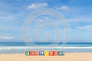 Word FEELGOOD in colorful alphabet blocks on tropical beach photo