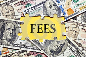 The word fees surrounded by puzzle pieces with dollar bill money. Fee costs, charges, commissions or penalties