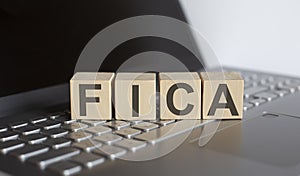 Word FICA made with letters on wooden blocks on the laptop