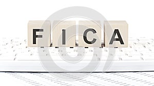 Word FICA made with letters on the wooden blocks on the laptop