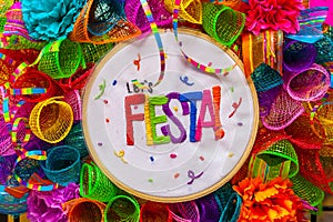 The word `fiesta` stitched in colorful letters on multicolored mash decorated with glitter and paper flowers photo