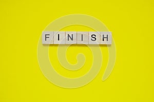 Word finish. Top view of wooden blocks with letters on yellow surface