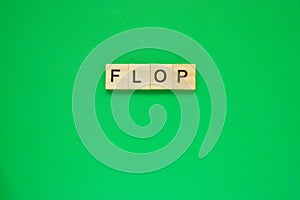 Word flop. Top view of wooden blocks with letters on green surface