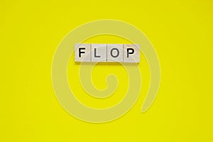 Word flop. Top view of wooden blocks with letters on yellow surface