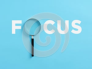 The word focus with a magnifying glass. Focusing on a target in business or education