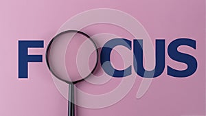 The word focus with a magnifying glass. Focusing on a target in business or education concept