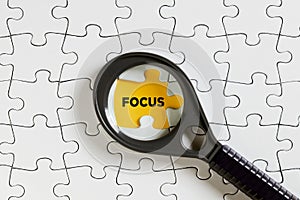 The word focus on missing puzzle piece with a magnifying glass