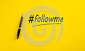 The word follow me or hashtag followme hand written with a black marker pen on yellow background photo