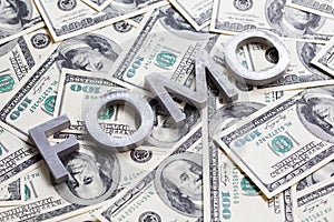 The word FOMO laid with aluminium letters on the US dollar banknotes background - with selective focus