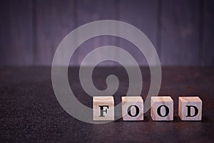 The word food on wooden cubes, on a dark background, light wooden cubes signs, symbols signs