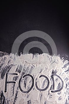 Word food written with flour on black background