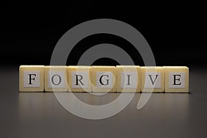 The word FORGIVE written on wooden cubes isolated on a black background