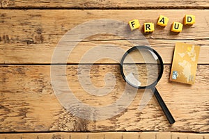 Word Fraud of yellow cubes with letters , credit card and magnifying glass on wooden background, flat lay. Space for text