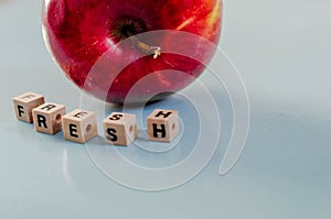 The word fresh written in cubes and an apple