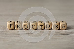 Word Fructose made of wooden cubes on table, closeup