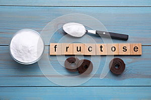 Word Fructose, sweet powder and fruit leather rolls on light blue wooden table, flat lay