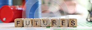 Word futures collected from wooden cubes with oil barrels and blurred business person in background.