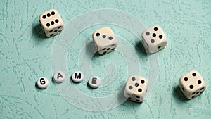 The word `Game` is composed of multicolored wooden letters and game dice on a mint background.