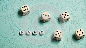 The word `Game` is composed of multicolored wooden letters and game dice on a mint background.