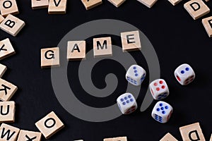 Word GAME with wooden letters on black Board with dice and letter in the circle