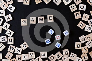 Word GAME with wooden letters on black Board with dice and letter in the circle