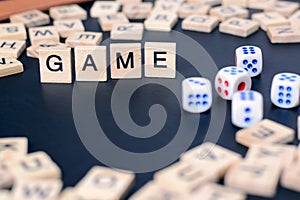 Word GAME with wooden letters on black Board with dice and letter in the circle