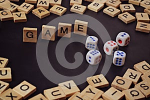 Word GAME with wooden letters on black Board with dice and letter in the circle