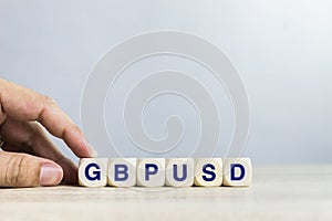 A word `GBPUSD` on a wooden table over the light wall