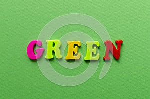 Word `green` from plastic colored magnet letters on green paper