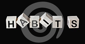 The word Habits written on wooden cubes and black background