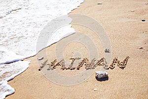 Word Hainan written in the sand seashore of tropical beach
