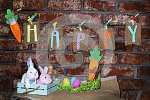 Word Happy on sackcloth tags hanging on a line with orange carrot, colorful Easter eggs, glass jar and easter bunny rabbit