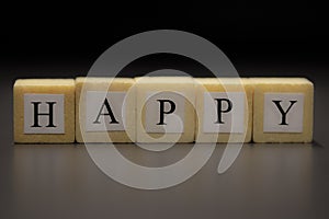 The word HAPPY written on wooden cubes isolated on a black background