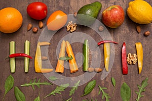 Word Health written with different vegetables, fruits, nuts and greens on rustic wooden background. Organic ingredients