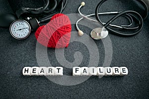 Word HEART FAILURE from white cubes with letters on dark background with red thread heart and tonometer. HEART FAILURE