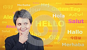 Word hello with different translations on the yellow wall. Multilingual woman learning and speaking many languages. International photo