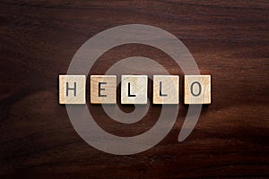 Words Hello Spelled out in Wooden Letter Blocks on Dark Walnut Wood Background photo