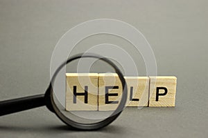 The word Help is made of wooden letters on a gray background. Selective focus